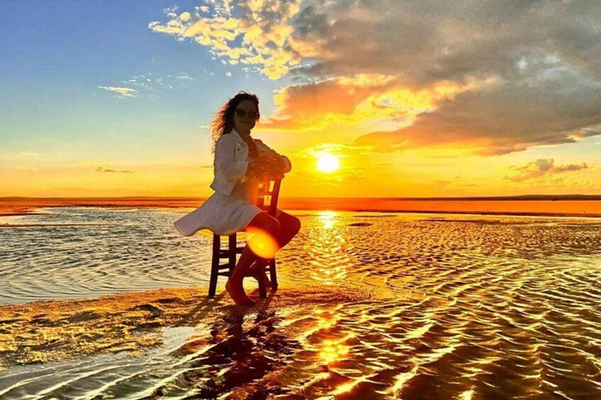 A person sitting on a chair by the water during sunset. 1