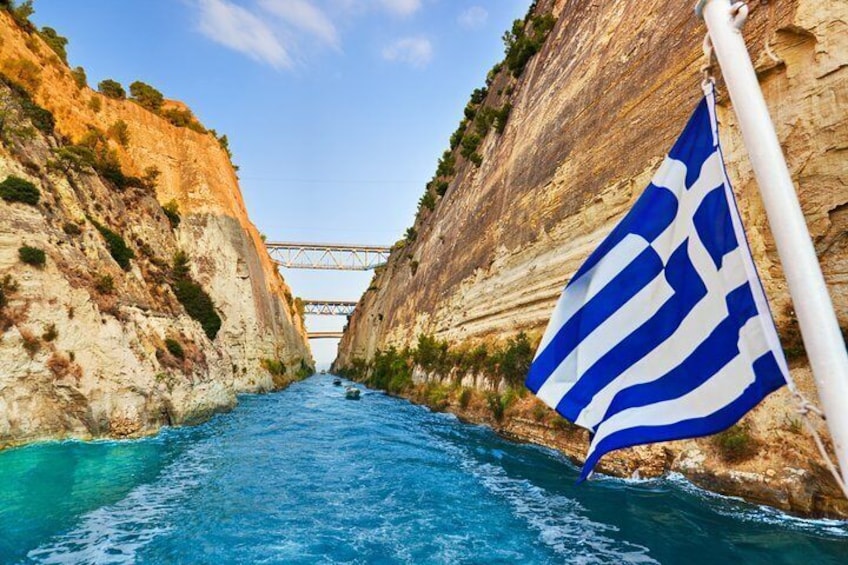A narrow waterway flanked by steep cliffs, a bridge in the distance, and a flag with blue and white stripes. 4