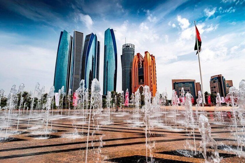 A cityscape with modern skyscrapers and a fountain display. 5