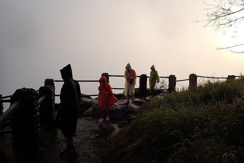 A group of people standing on a rocky path near a body of water during sunset. 3