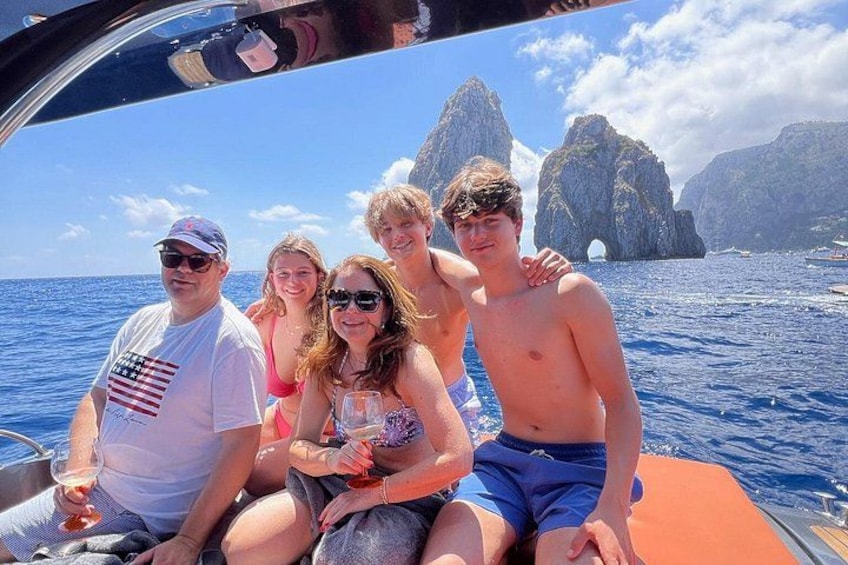 A group of people on a boat with a clear view of the ocean and rocky formations in the background. 5