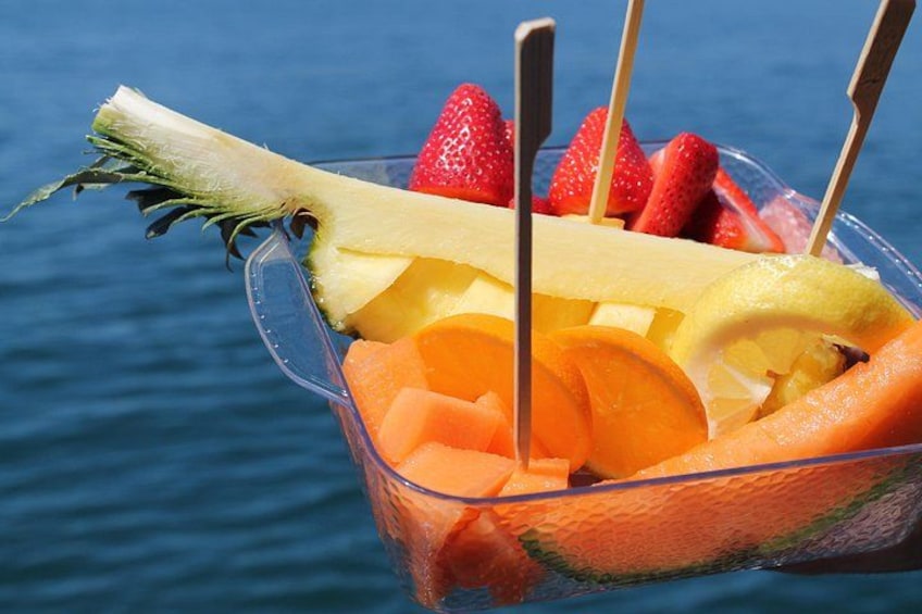 A fruit bowl with pineapple, strawberries, and orange slices on a boat. 2