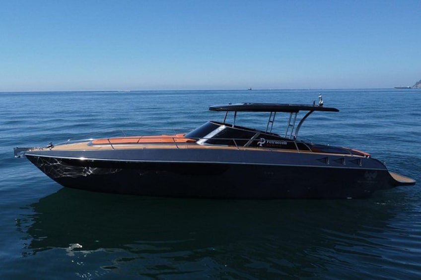 A sleek black speedboat on calm water with a clear sky and distant land in the background. 3