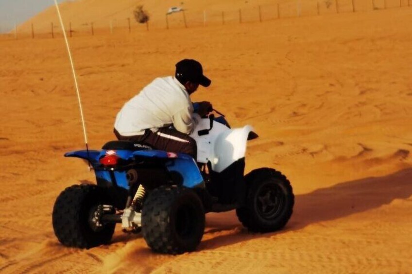 A person riding a blue and white ATV in a sandy desert landscape. 4