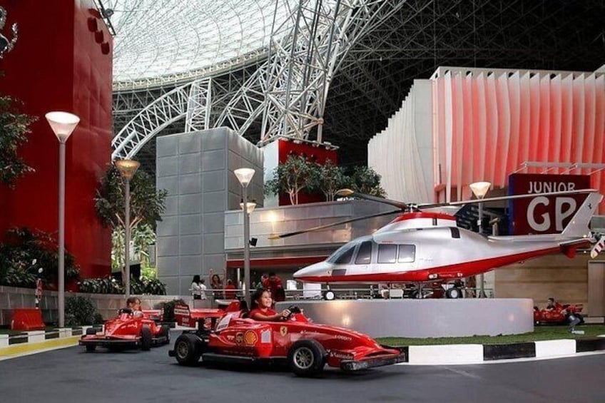 A red race car, a helicopter, and a building with a red and white facade. 1