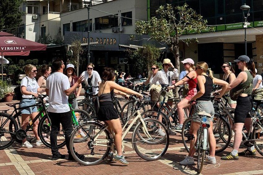 A group of people on bicycles in an outdoor setting with buildings in the background. 5