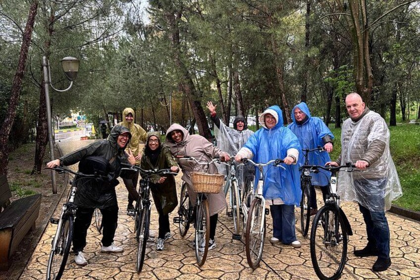 A group of people on bicycles in a park with trees and a paved path. 2