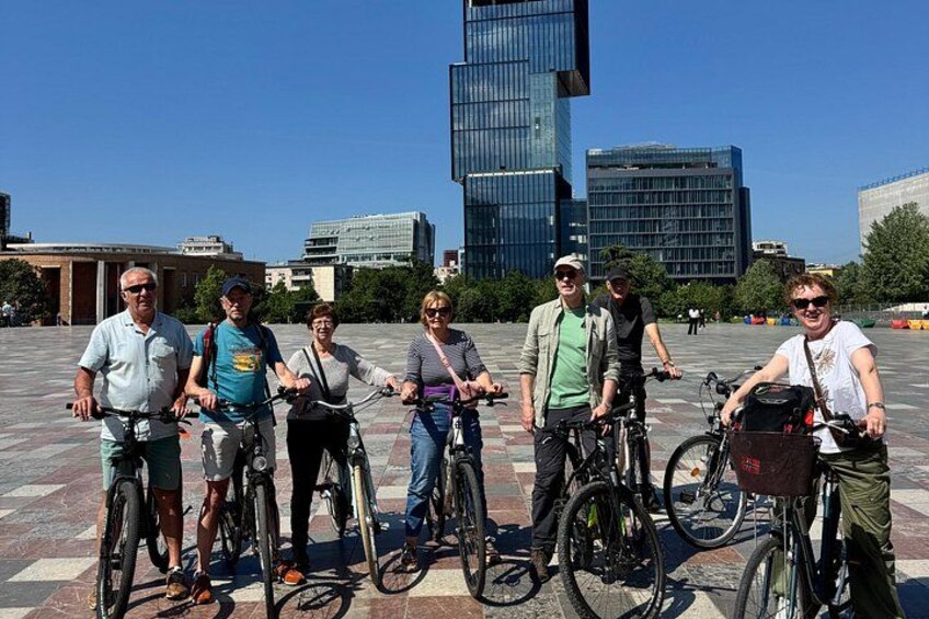 A group of people on bicycles in an urban setting with modern buildings in the background. 3