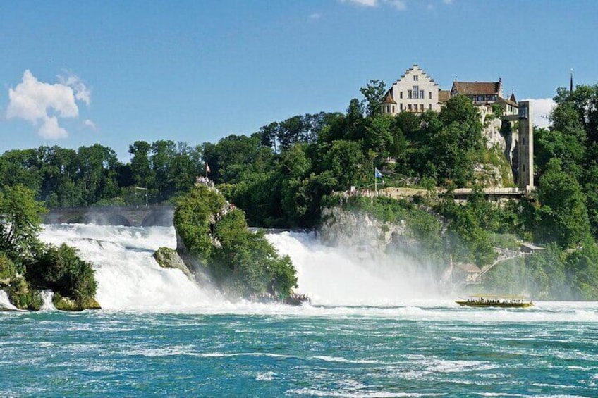 Una cascata che si getta in un fiume, circondata da una vegetazione rigogliosa e un edificio storico a picco sulla rupe. 5