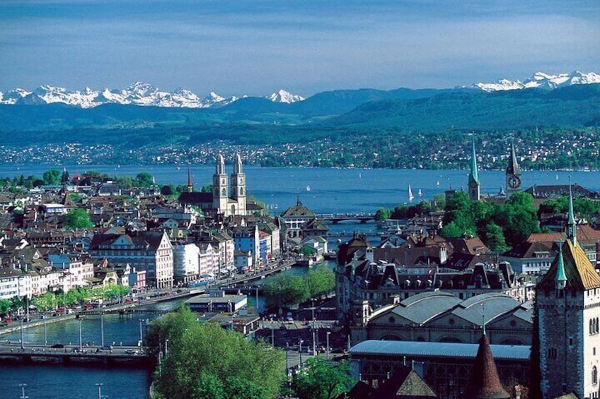 Una vista panoramica di una città con un fiume, edifici storici e montagne sullo sfondo. 4