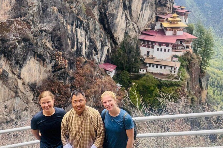 A group of people standing in front of a mountain with a monastery on top. 2