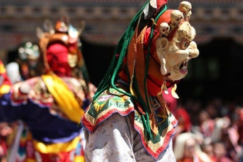 A person in colorful traditional attire with a mask, likely participating in a cultural event. 1