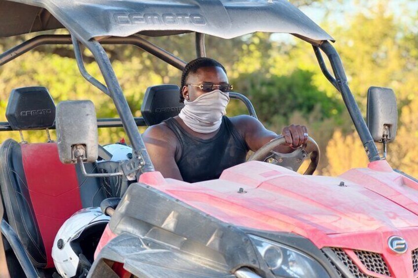 A person driving a red and black vehicle with a canopy. 4