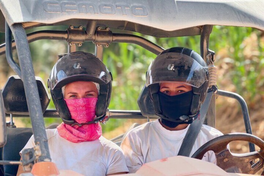 Two people in a vehicle with a steering wheel and a dashboard. 2