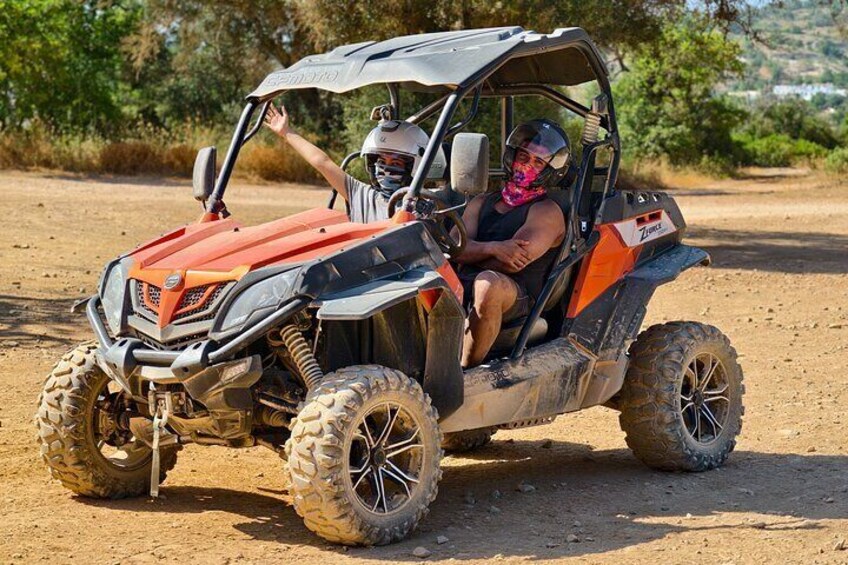 A person in a red and black off-road vehicle on a dirt road. 5