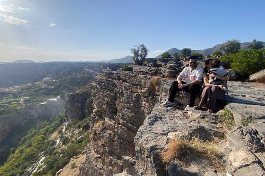 Eine Gruppe von Personen sitzt auf einer felsigen Klippe mit Blick über ein Tal. 3