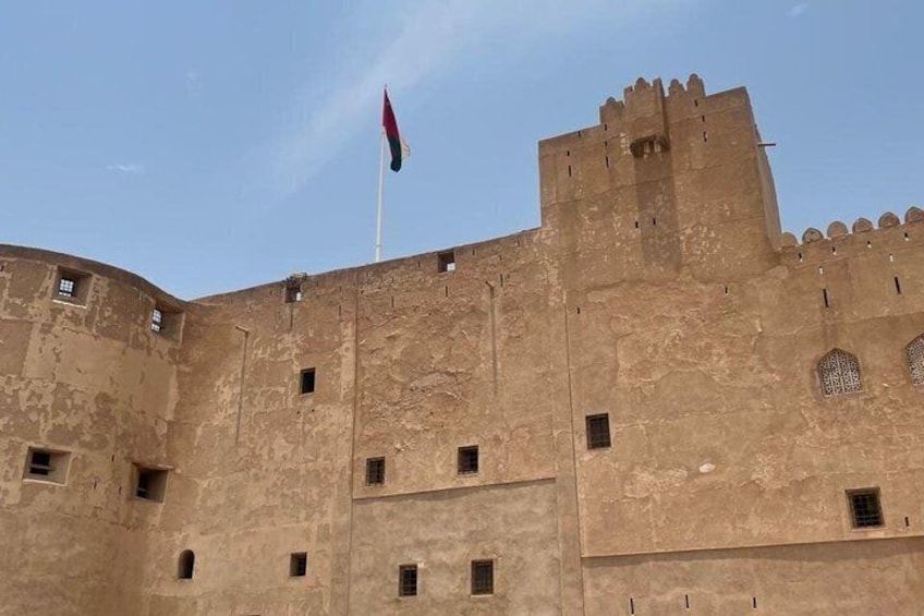 Una fortaleza grande e histórica con una bandera en la parte superior, que presenta almenas merlonadas y numerosas ventanas pequeñas. 4