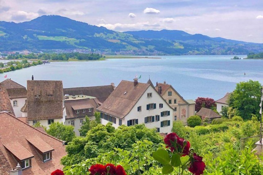 A lakeside village with traditional houses, lush greenery, and mountains in the background. 2