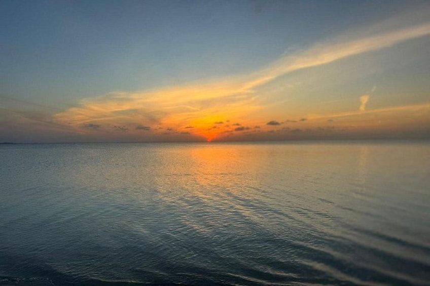 A calm sea at sunset with a clear horizon and a few clouds. 2
