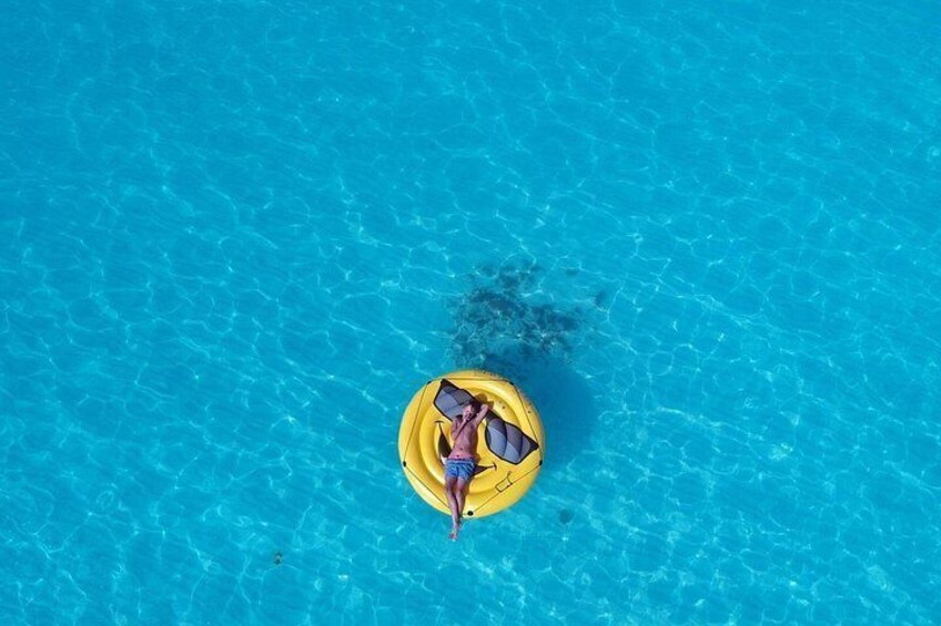 A person floating on a yellow raft in a clear blue pool. 2