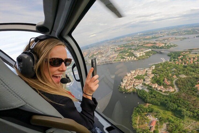 A person in a helicopter cockpit with a view of a river and a cityscape. 3