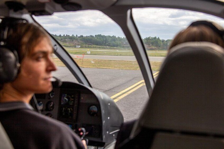 A helicopter cockpit with a view of a runway and trees in the background. 3