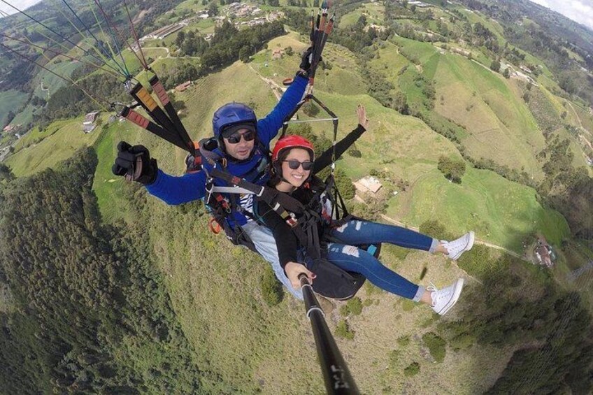 Two people skydiving with parachutes over a hilly landscape. 4