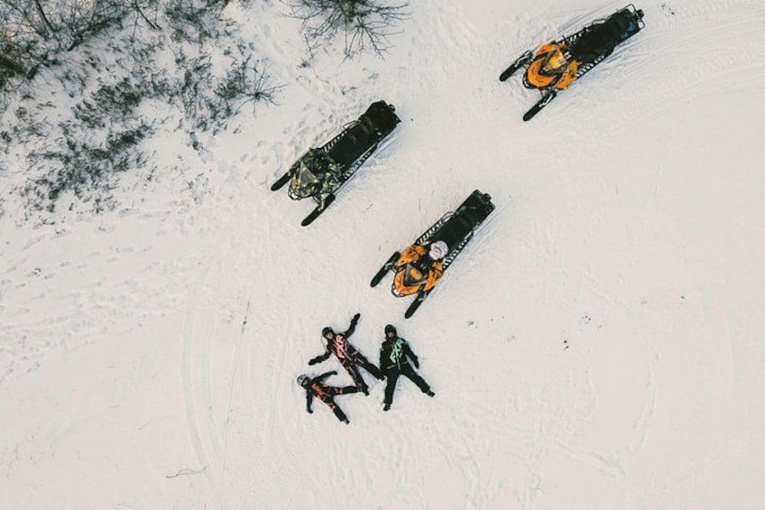 A snowy landscape with four snowmobiles and two people. 3