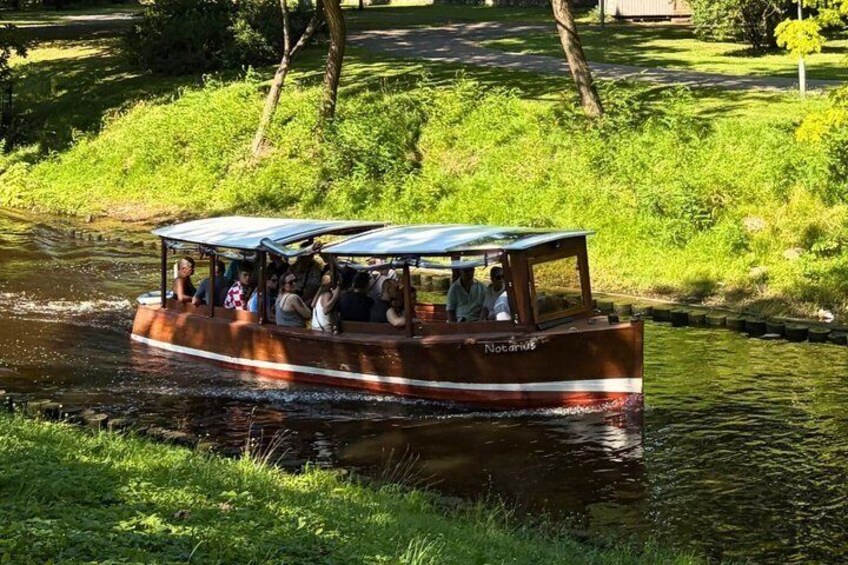A narrowboat with passengers on a river surrounded by greenery. 2