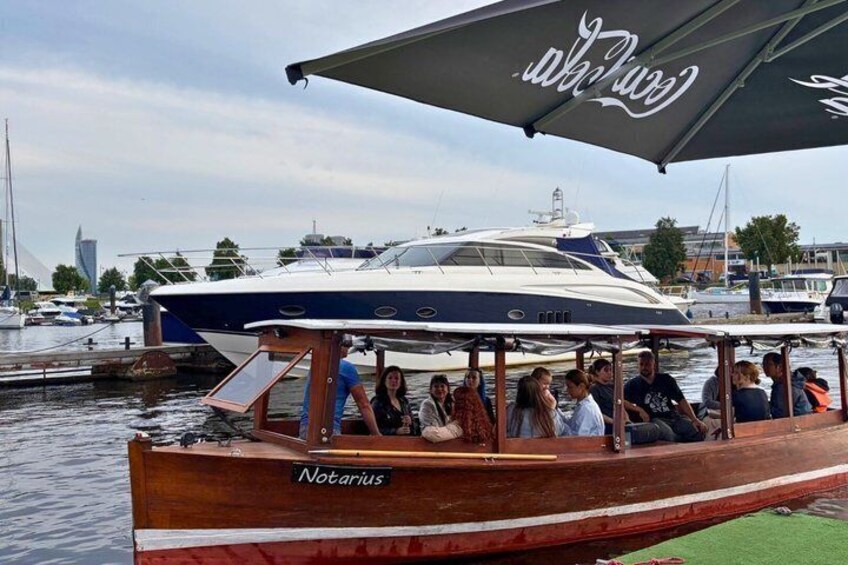 A boat named Notarius docked at a marina with people on board. 3