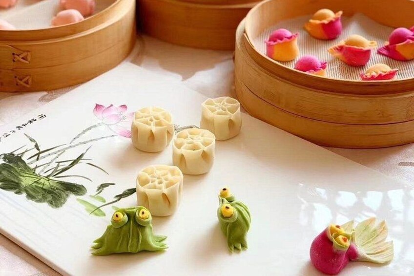 Una vaporera de bambú con albóndigas, un plato decorativo con una figurita de rana e ilustración de flor de loto. 2