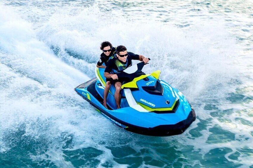 Two people riding a blue and yellow jet ski on a body of water. 5
