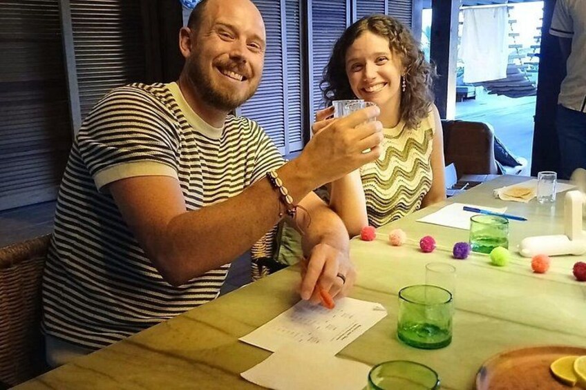 Two people sitting at a table with papers and colorful pom-poms. 2