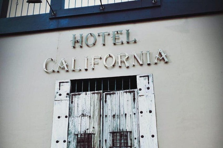 Un edificio con un letrero que dice 'HOTEL CALIFORNIA' sobre una puerta desgastada. 5