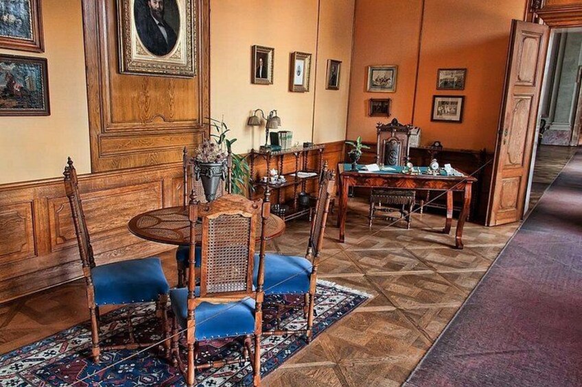 A room with wooden furniture, a blue sofa, and patterned rugs. 2
