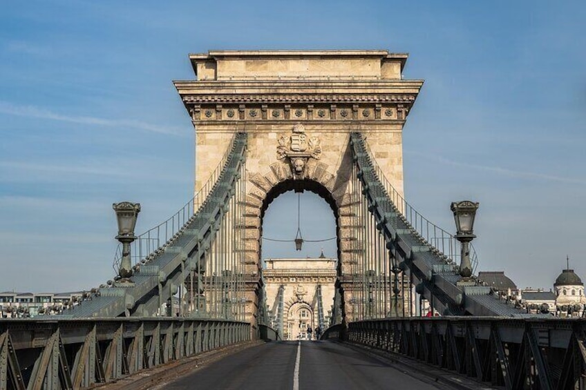 A large stone bridge with a central archway and suspension cables. 5