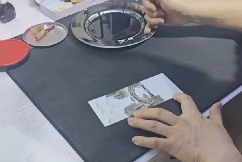 Una persona cubriendo una imagen impresa sobre una superficie negra con una lámina transparente. 2