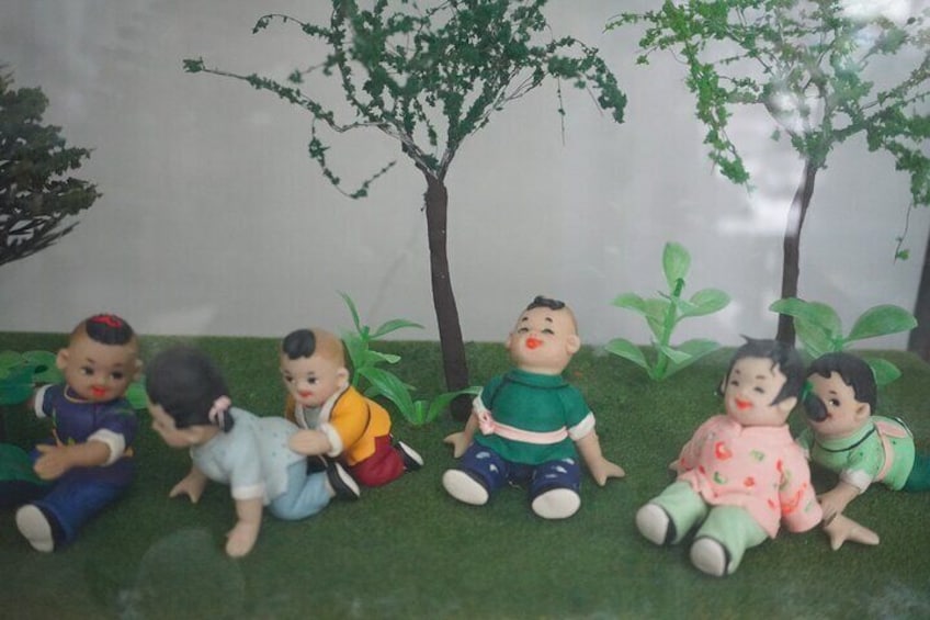 Un grupo de niños sentados sobre césped artificial, con árboles al fondo. 1