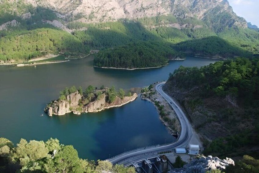 Un camino serpenteante junto a un lago rodeado de colinas boscosas. 2