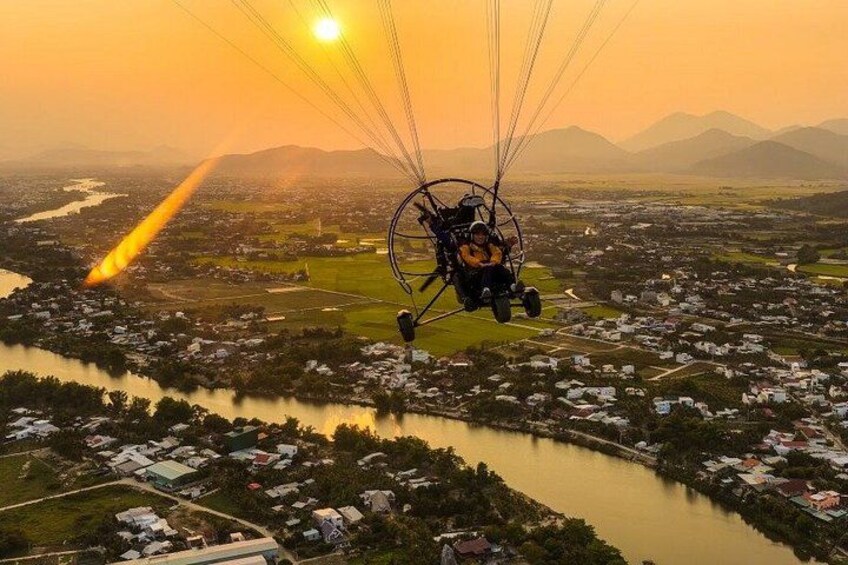 A paragliding activity over a river and town during sunset. 1