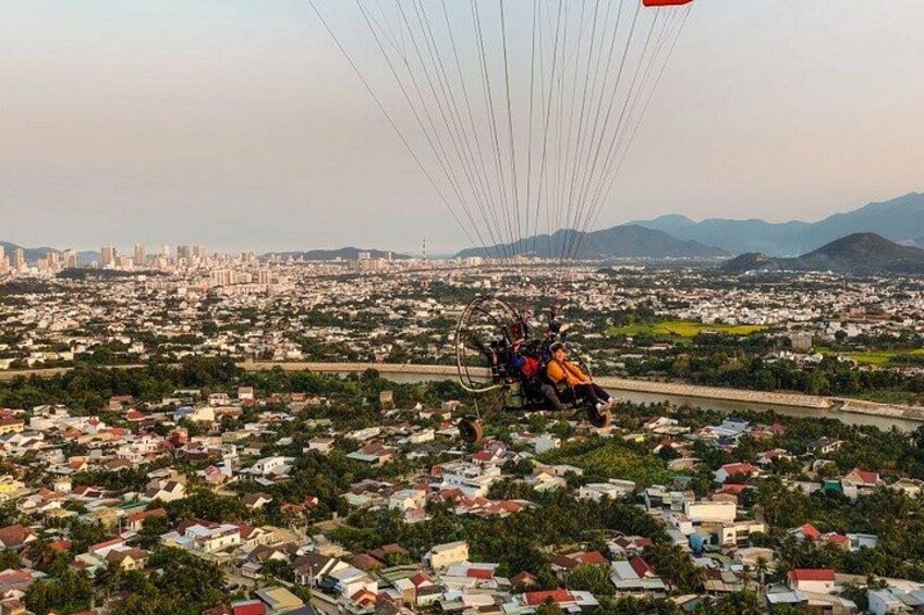 A paragliding activity over a cityscape with visible buildings and a river. 3