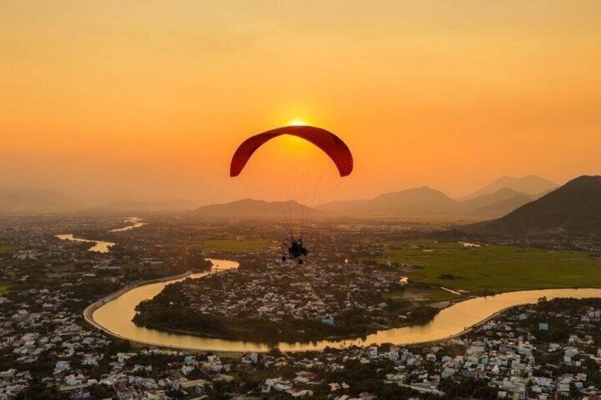 A paraglider over a cityscape at sunset. 1