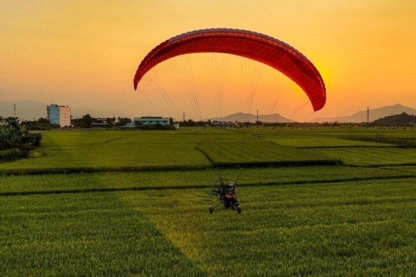 A person paragliding over a field with a sunset in the background. 5