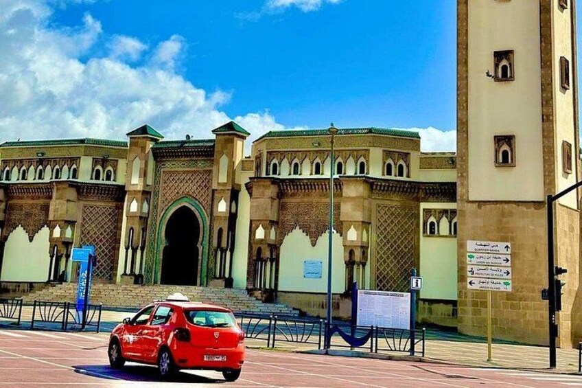 Un coche rojo estacionado frente a un edificio histórico con arcos y una torre del reloj. 3