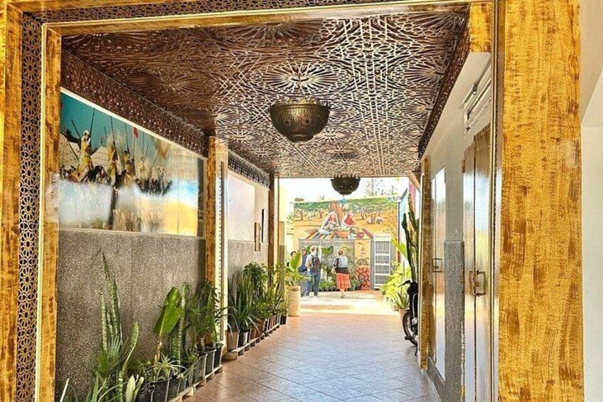 Un pasillo con techo estampado, plantas en macetas y un mural en la pared izquierda. 4