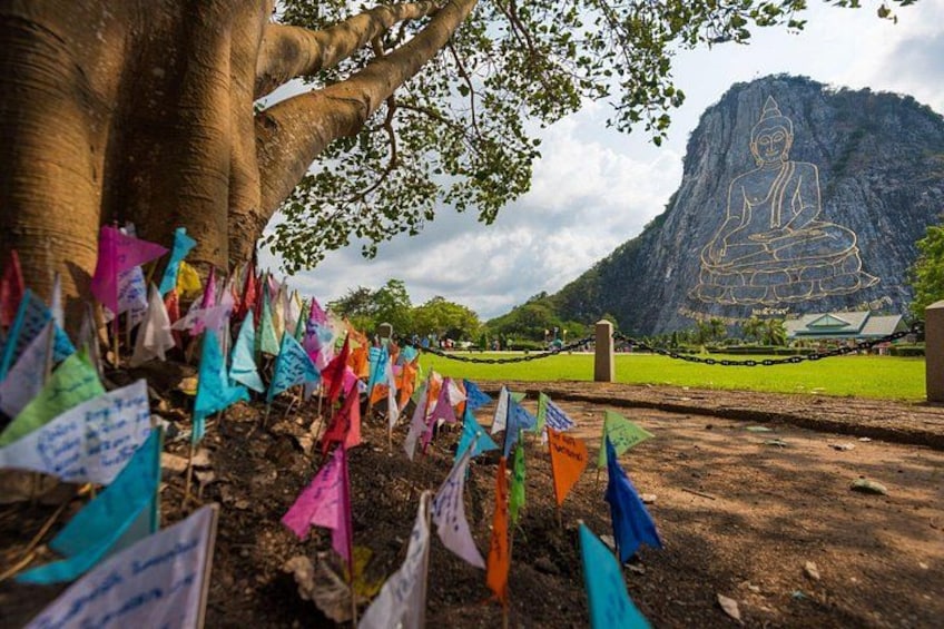 Un árbol grande, banderas coloridas y una montaña con una estatua. 1