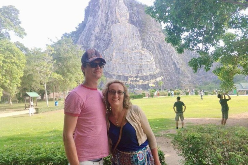 Una gran formación rocosa con una figura esculpida, un parque con césped y gente de fondo. 4