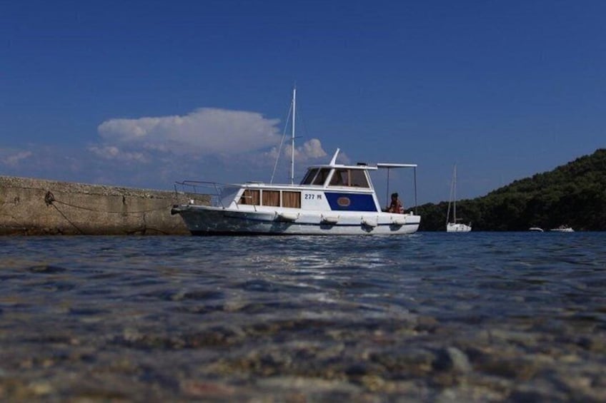 Ein Boot liegt an einem Steg, mit blauem Himmel und einer bewaldeten Insel im Hintergrund. 3