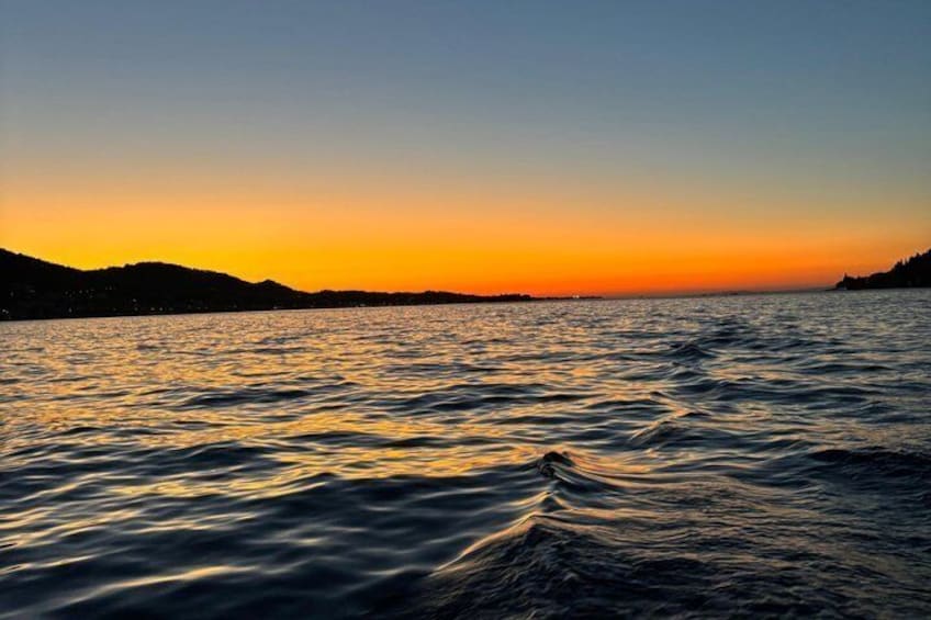 Ein Sonnenuntergang über einem Gewässer, im Hintergrund Hügel. 4