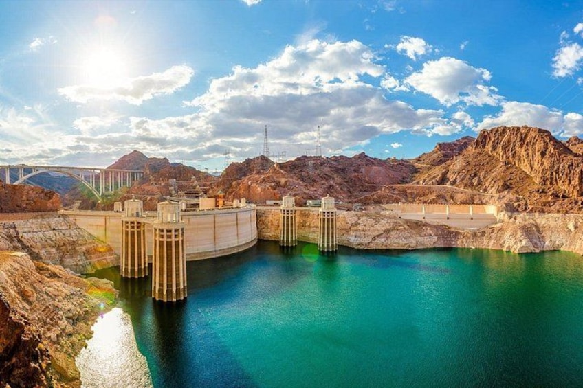 A hydroelectric dam with multiple water gates, a bridge, and a mountainous landscape. 1